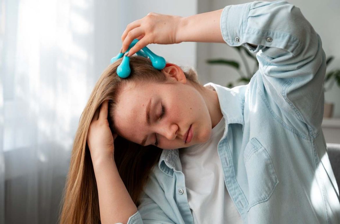 Femme pratiquant un massage crânien pour améliorer sa concentration au travail à l'aide d'un appareil manuel bleu.