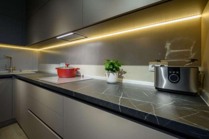 Un plan de travail d'angle moderne en marbre noir veiné dans une cuisine équipée.